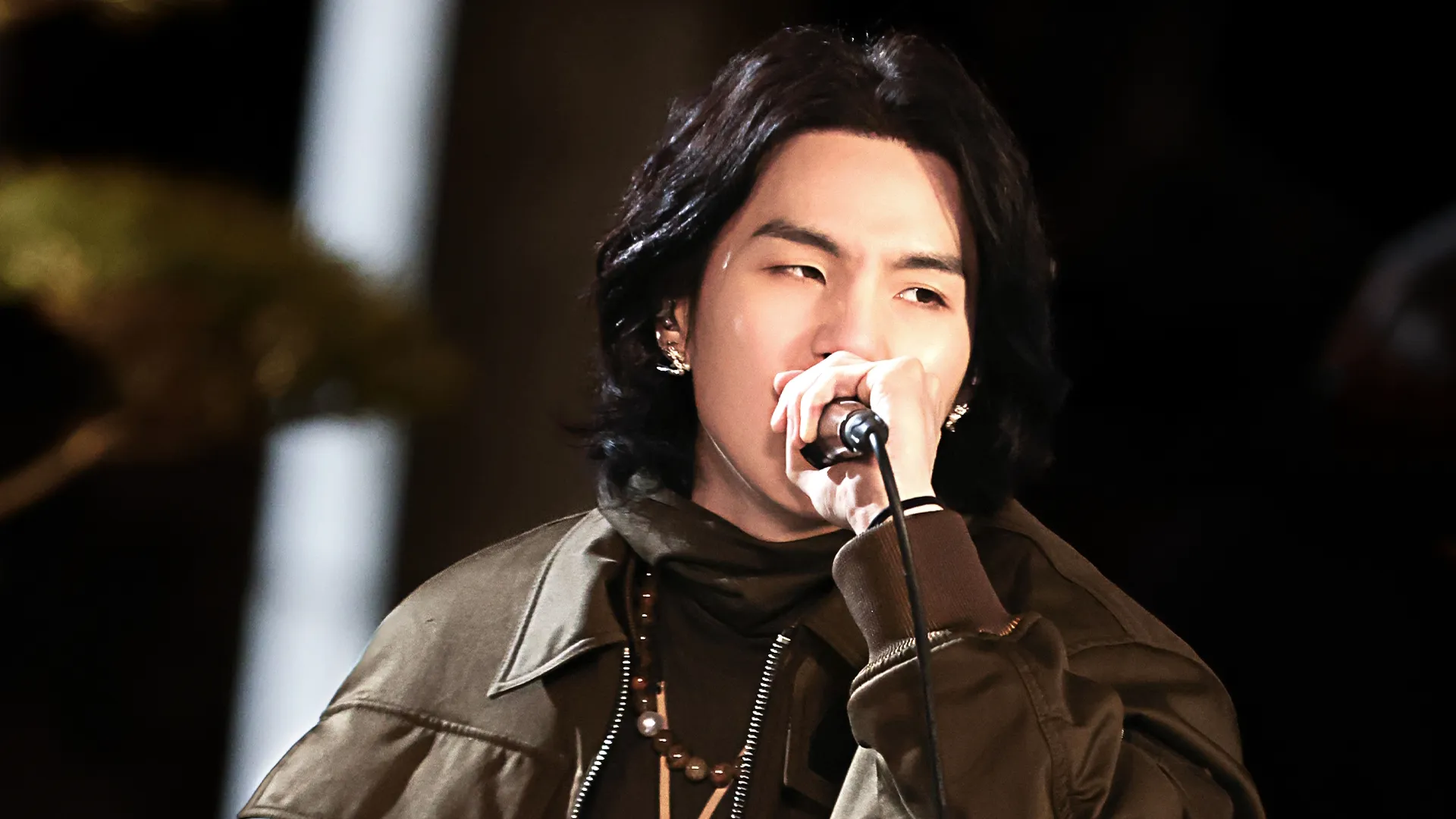 SUGA performs with the mic held up to his mouth.