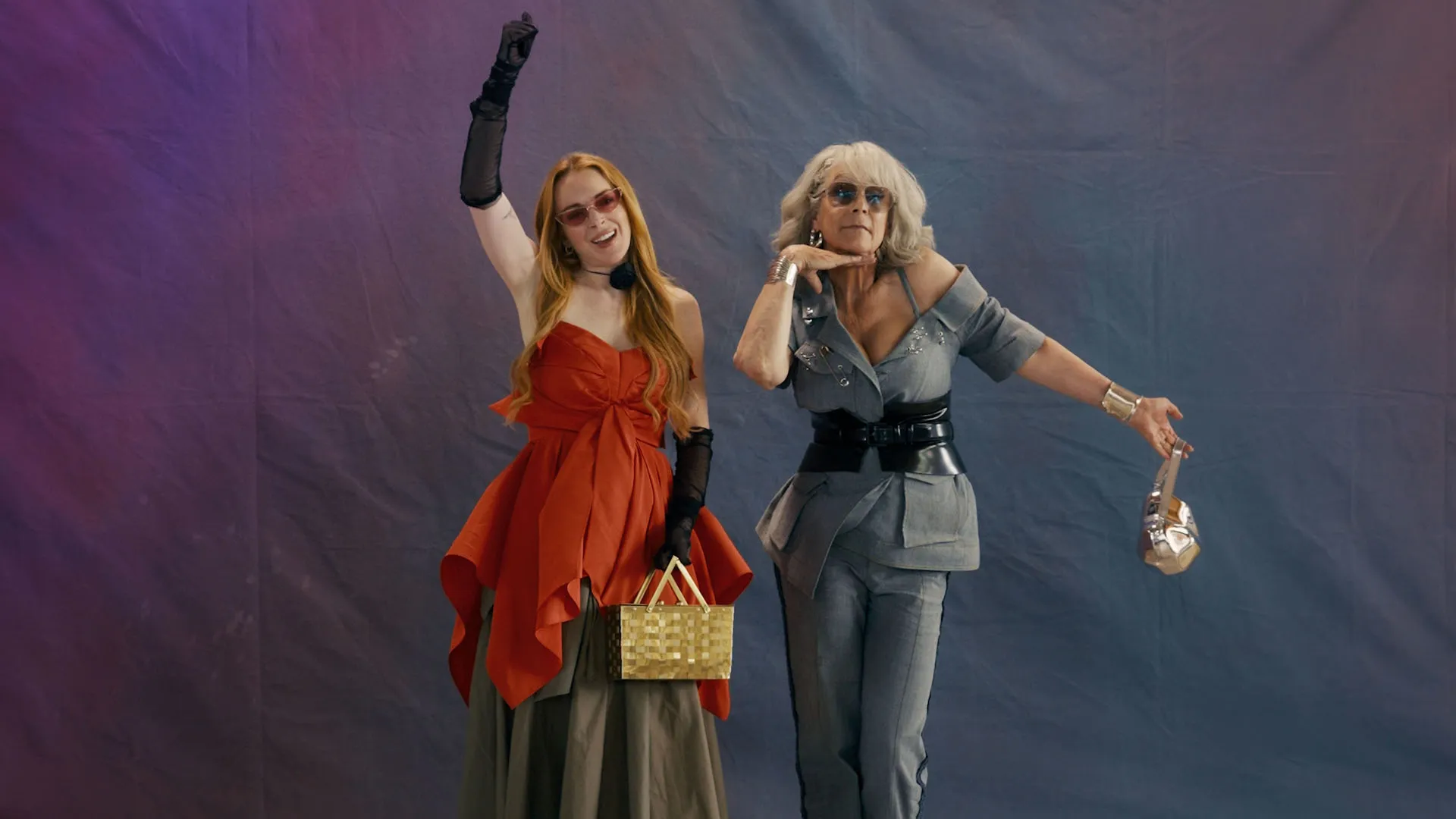 Anna (Lindsay Lohan) and Tess Coleman (Jamie Lee Curtis) pose next to each other in front of a purple background.