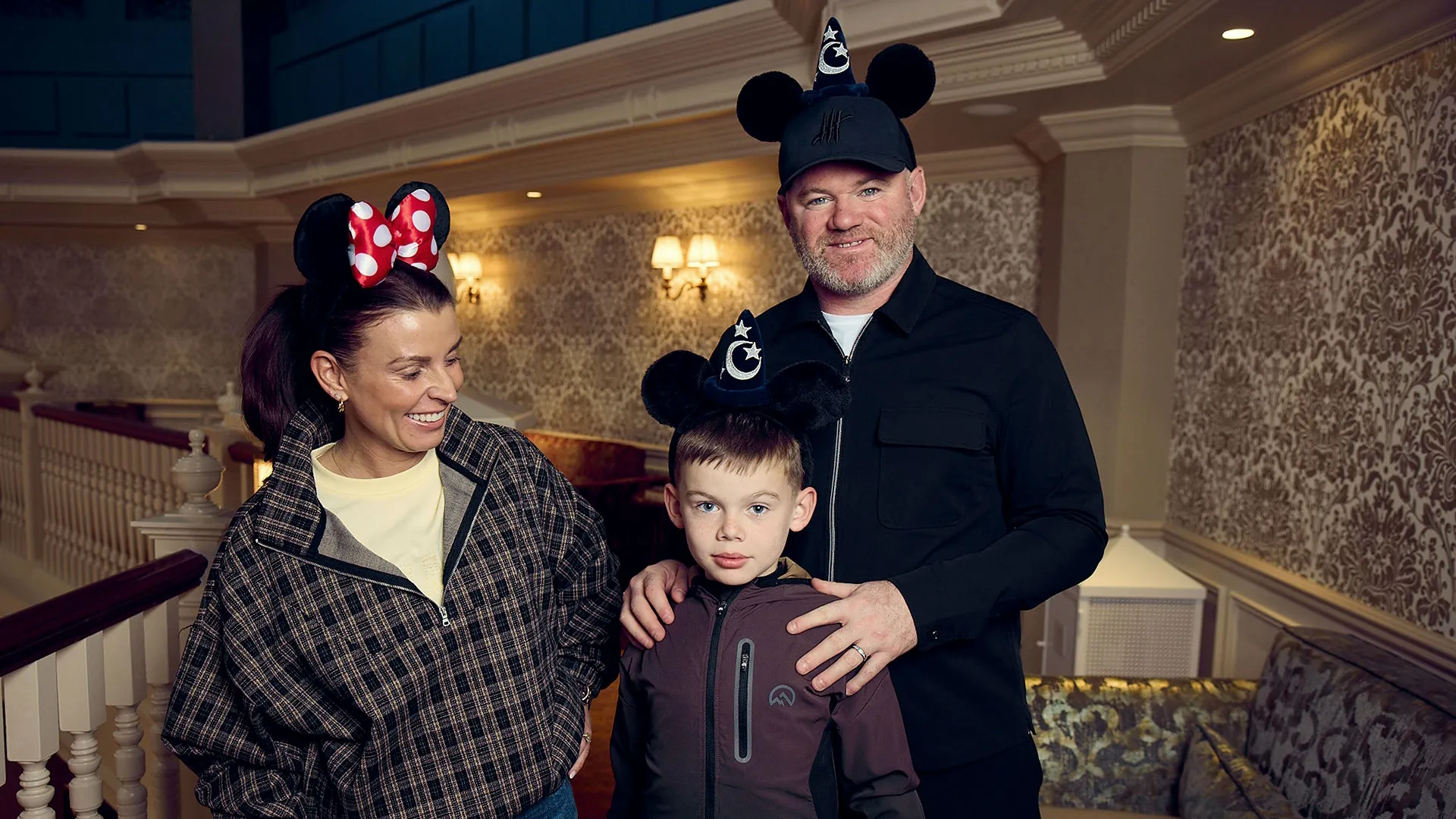 Coleen and Wayne Rooney pose with their youngest son wearing Mickey Mouse ear headbands during a visit to Disneyland Paris.