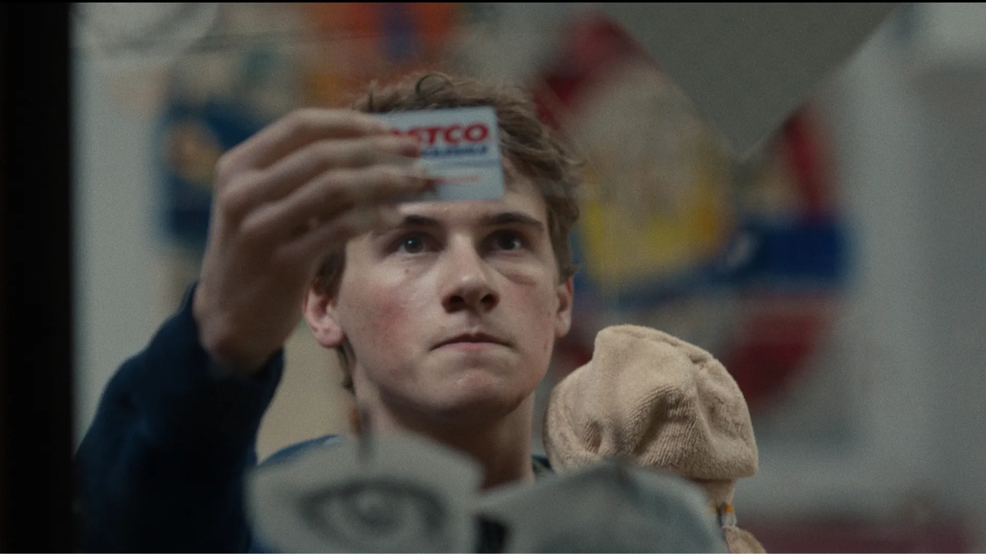 Sonny (Sam Nivola) holding up a Costco card