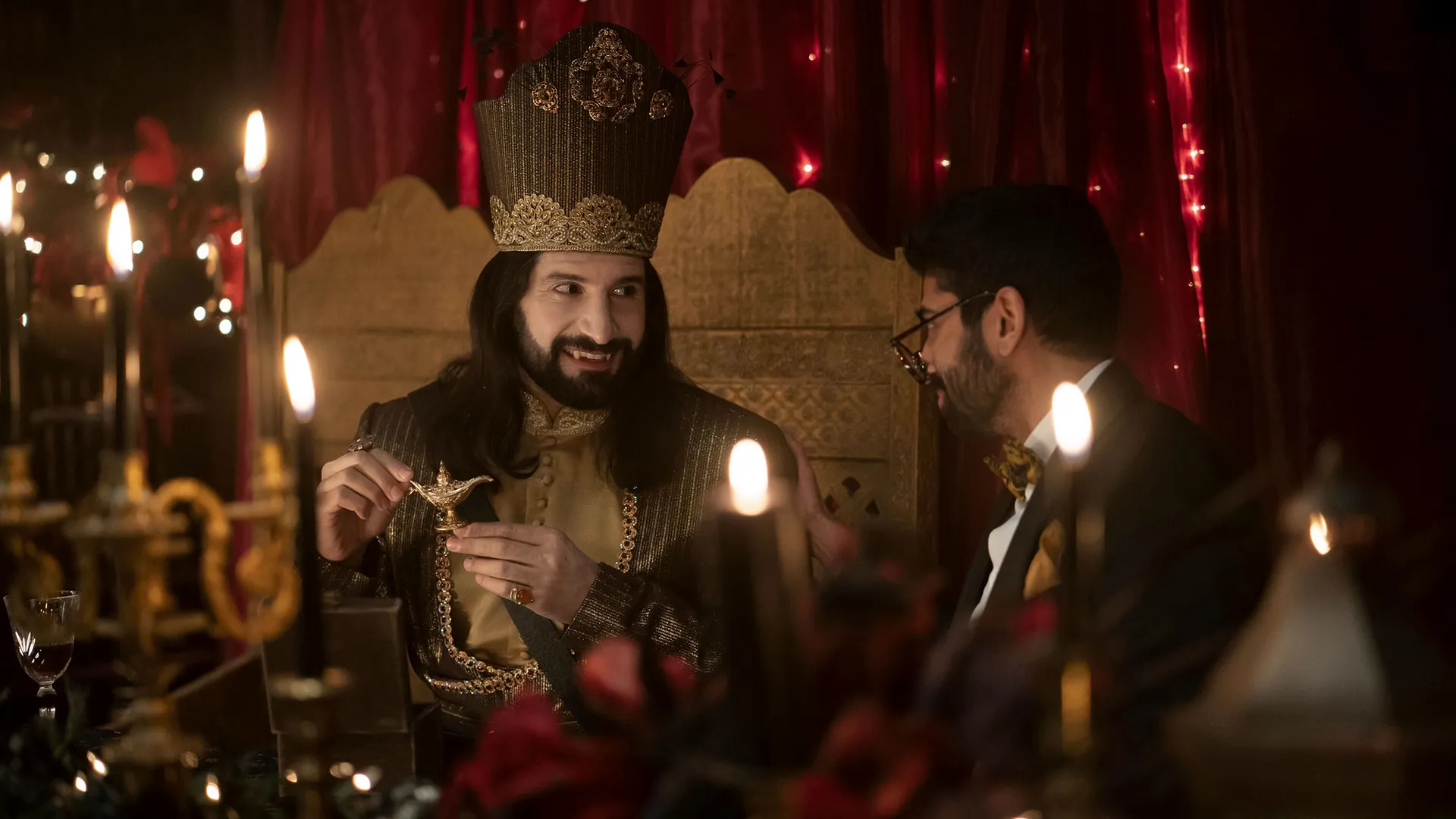 Nandor (Kayvan Novak) with a wry smile wearing regal clothing.