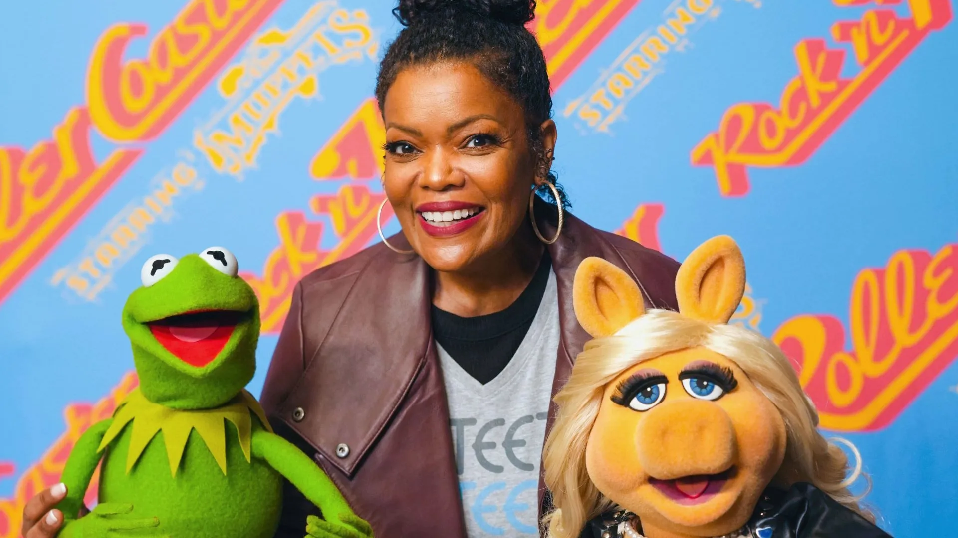 This image features actor Yvette Nicole Brown posing with the iconic Muppets, Kermit the Frog and Miss Piggy.