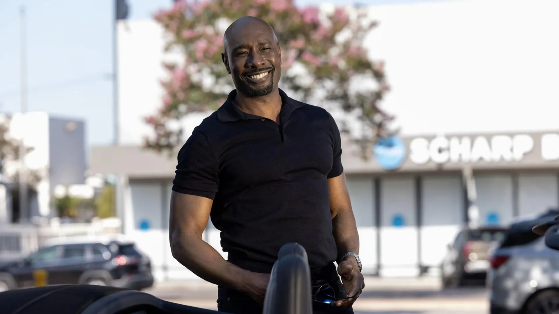 Morris Chestnut as Corey cash, smiling and wearing a black polo shirt