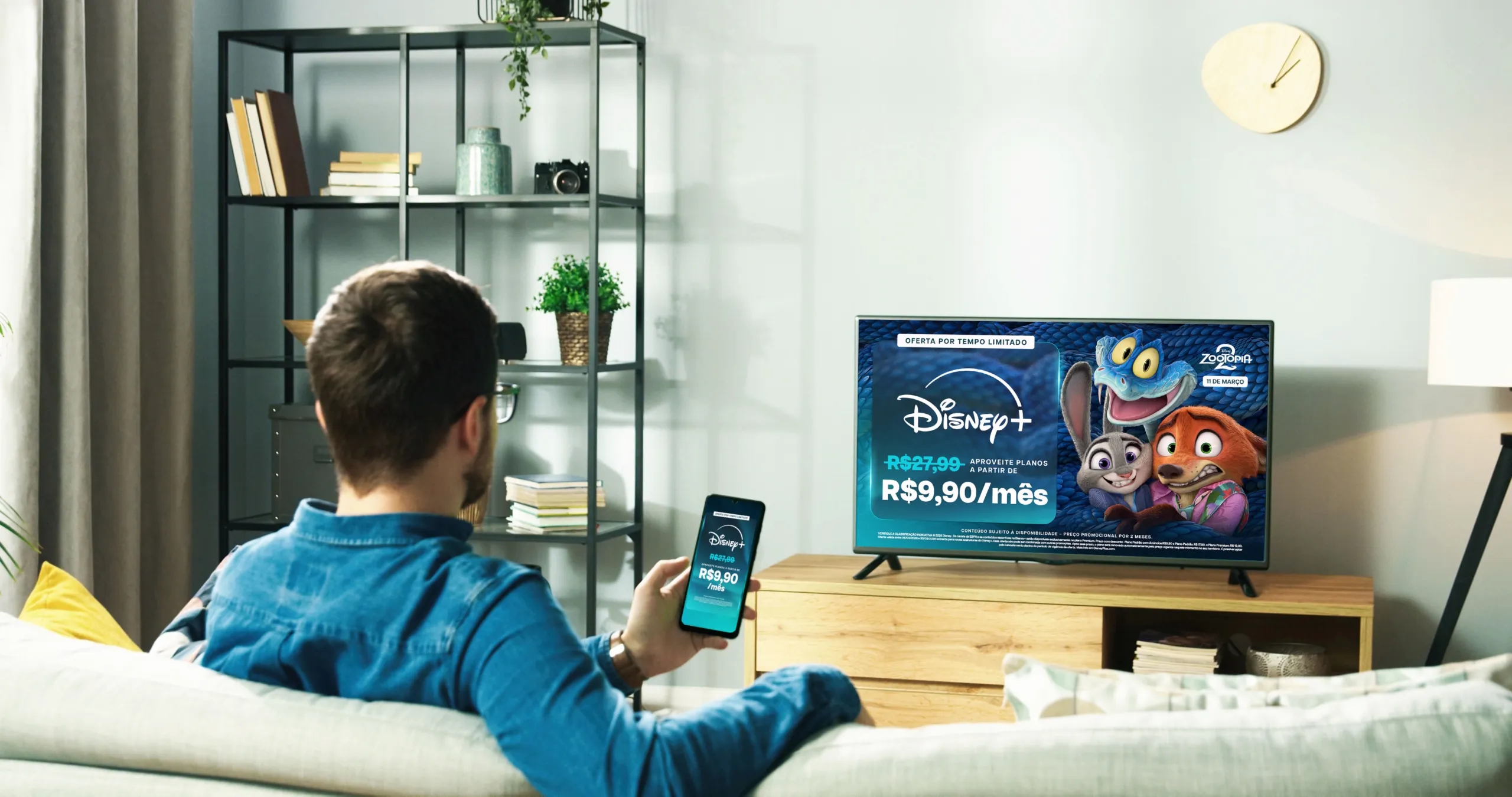 Man watching television in his living room, the TV showcases the promo for 3 months bundle offer and available titles such as Zootopia 2 (Disney+) and Secret Lives of Mormon Wives (Hulu).
