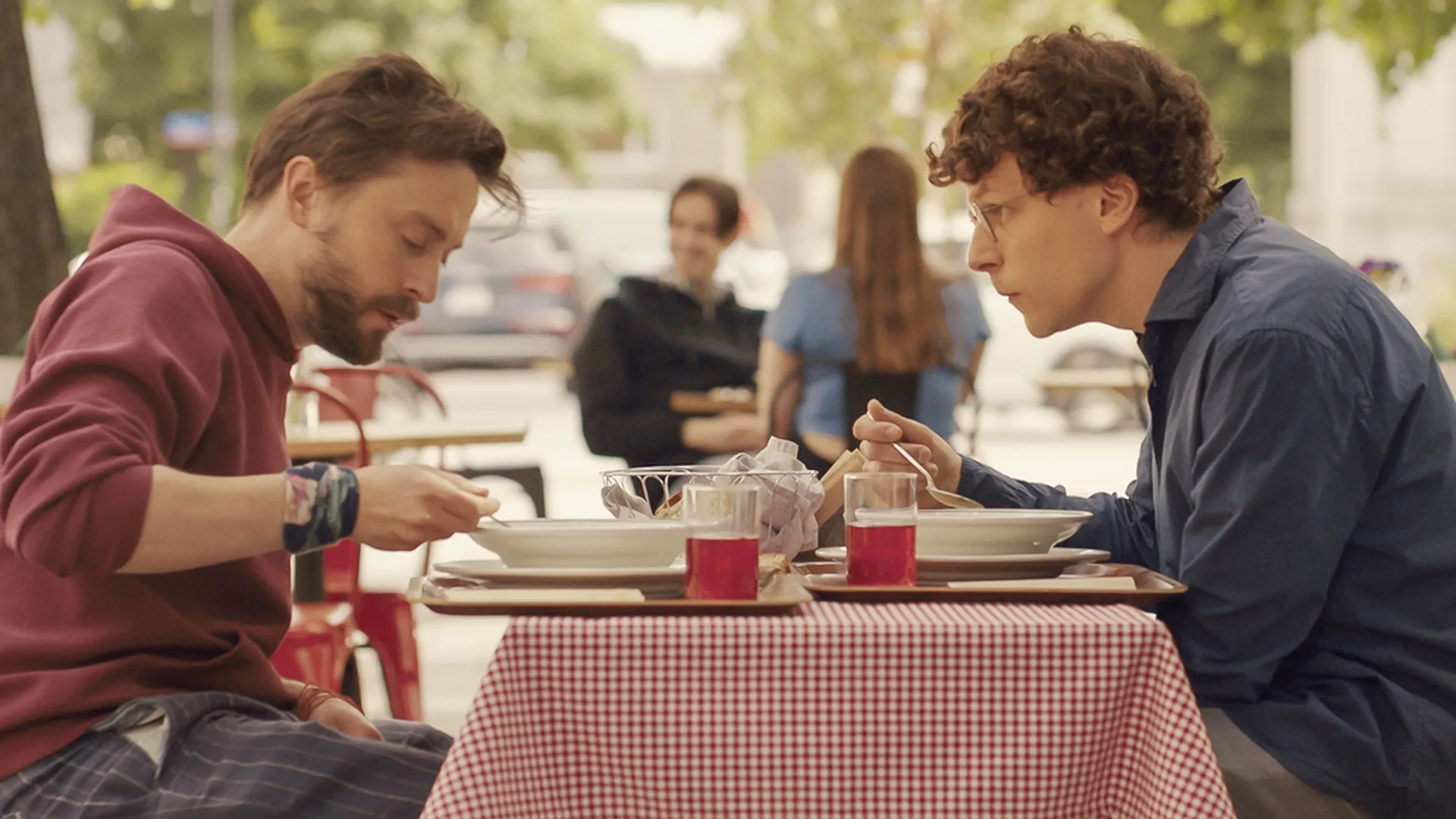 Benji (Kieran Culkin) with his arms wrapped around his cousin David (Jesse Eisenberg).