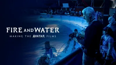 James Cameron is seen from behind, giving direction to a group of performers in high-tech gear in a swimming pool