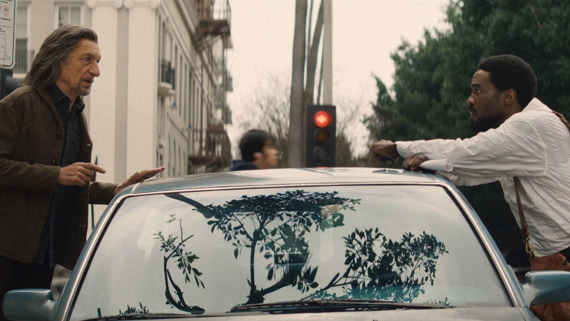 Wonder Man (Yahya Abdul-Mateen II) and Trevor Slattery (Ben Kingsley) talk over the roof of a car