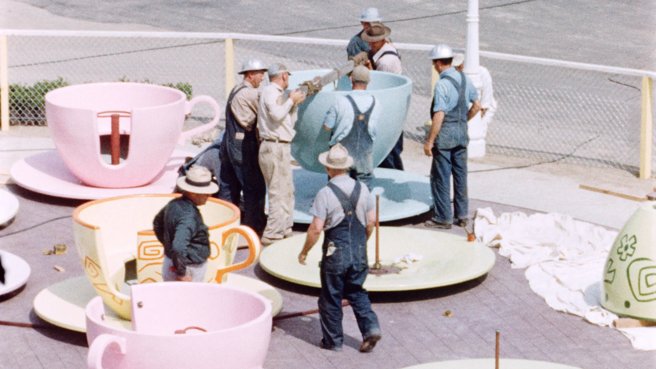 This image captures construction workers assembling the teacups for the Mad Tea Party ride during the final year of Disneyland's construction in Anaheim, California. 