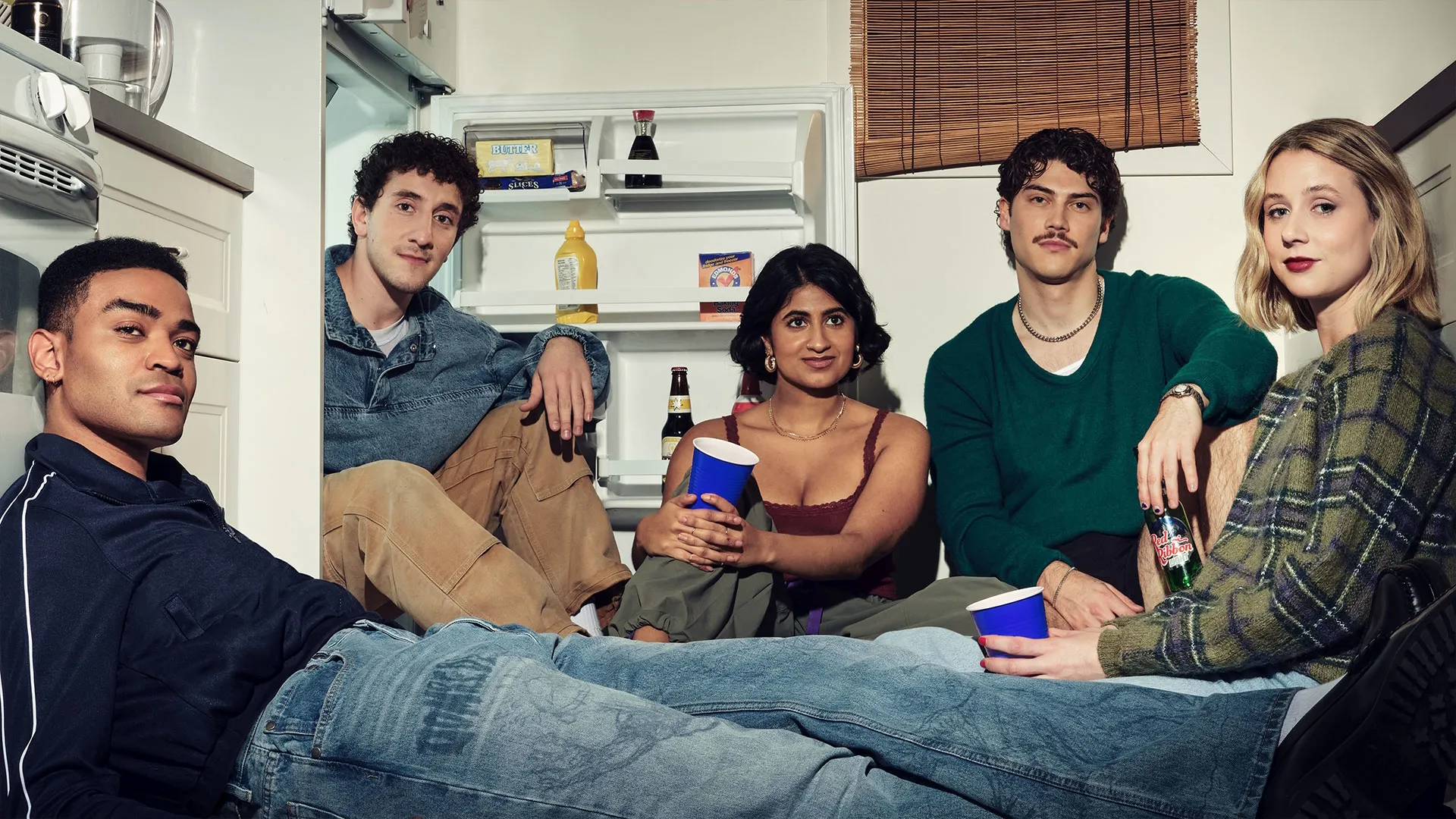Promotional image for Adults featuring five young adults gathered on the floor in front of an open refrigerator.