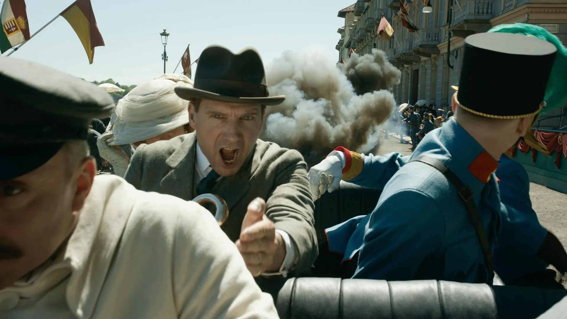 A bomb goes off in the background as Orland Oxford (Ralph Fiennes) tries to get Archduke Franz Ferdinand to safety following an assassination attempt.