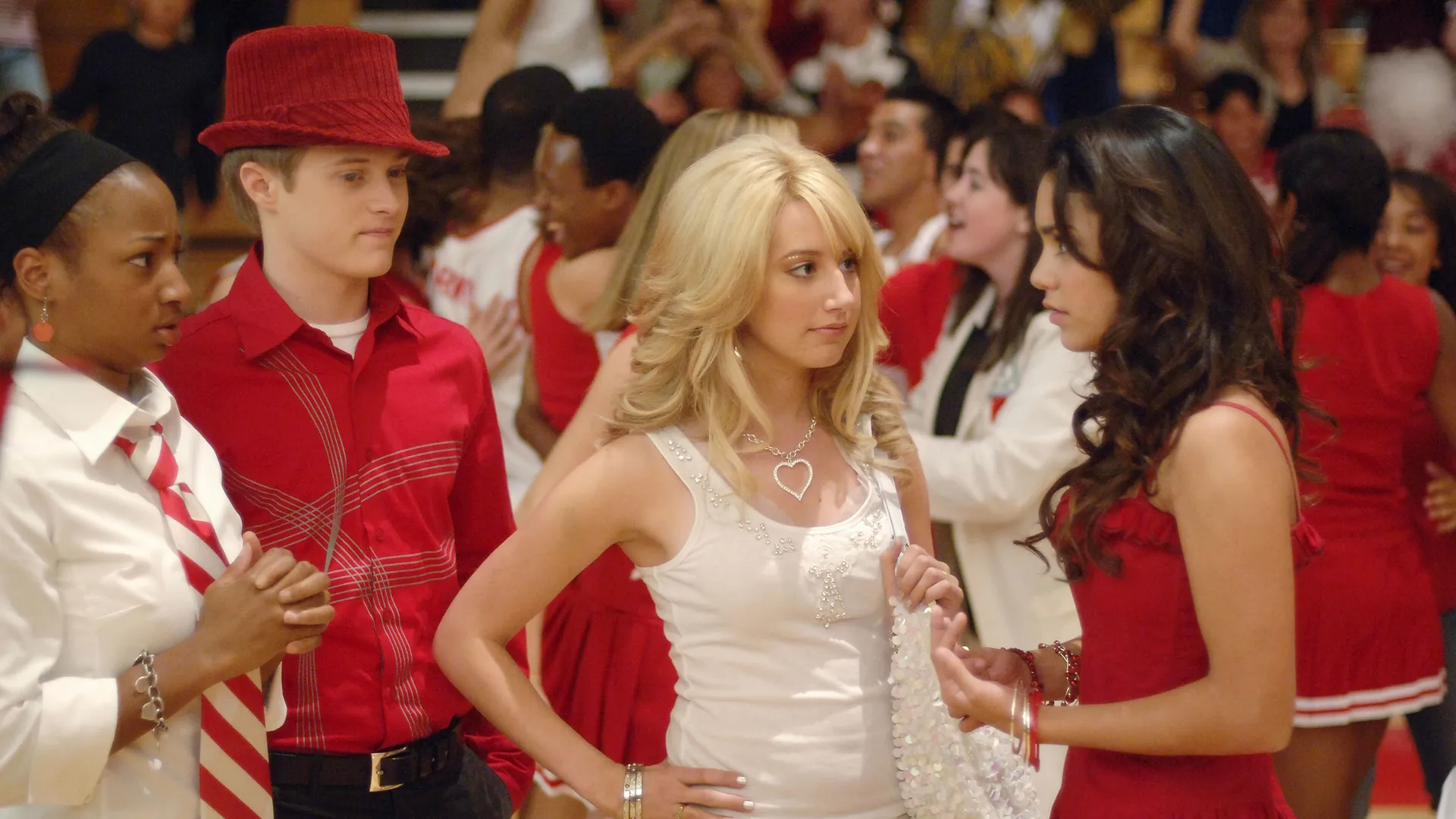 Gabriella (Vanessa Hudgens) talks to Sharpay (Ashley Tisdale), Ryan (Lucas Grabeel), and Taylor (Monique Coleman) in the school gymnasium