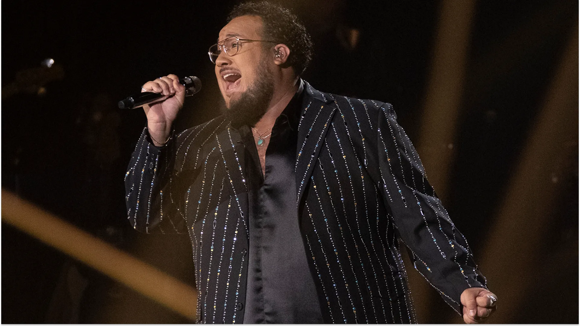 Closeup of American Idol finalist Jordan McCullough singing on stage, in a sequinned pinstripe suit jacket