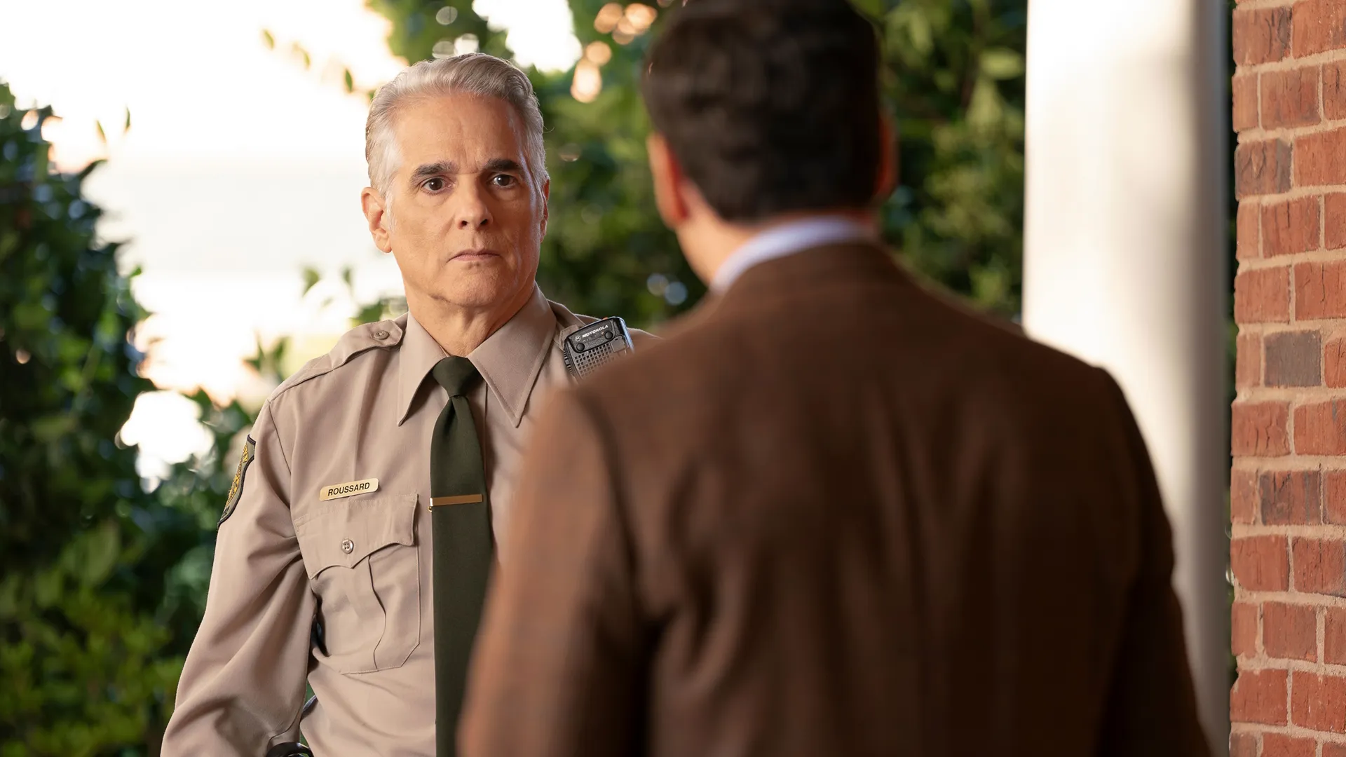 Sheriff Caleb Roussard (Yul Vazquez) looks at Will (Ramón Rodríguez), who has his back to the viewer.