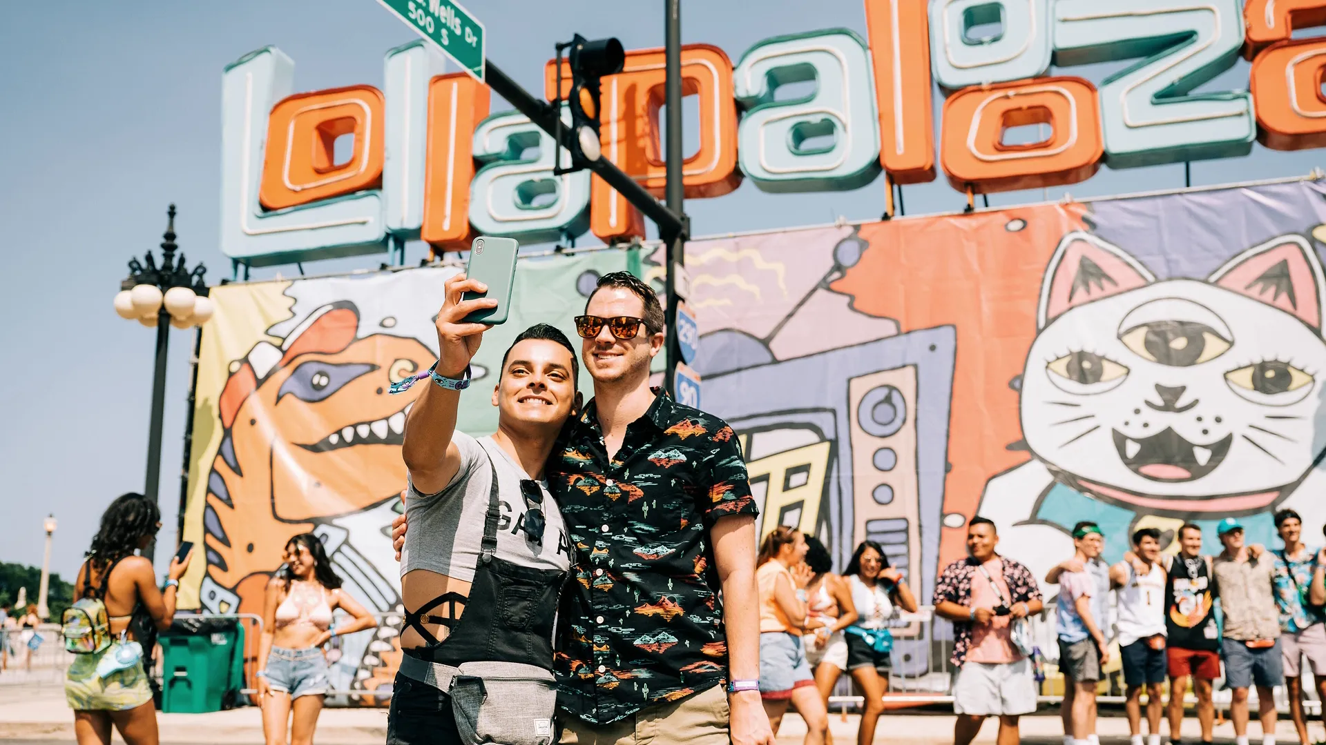 Two men take a selfie in front of the Lollapalooza sign
