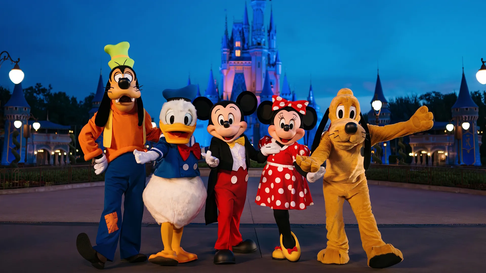 Goofy, Donald, Mickey, Minnie, and Pluto pose in front of Cinderella's Castle at Walt Disney World.