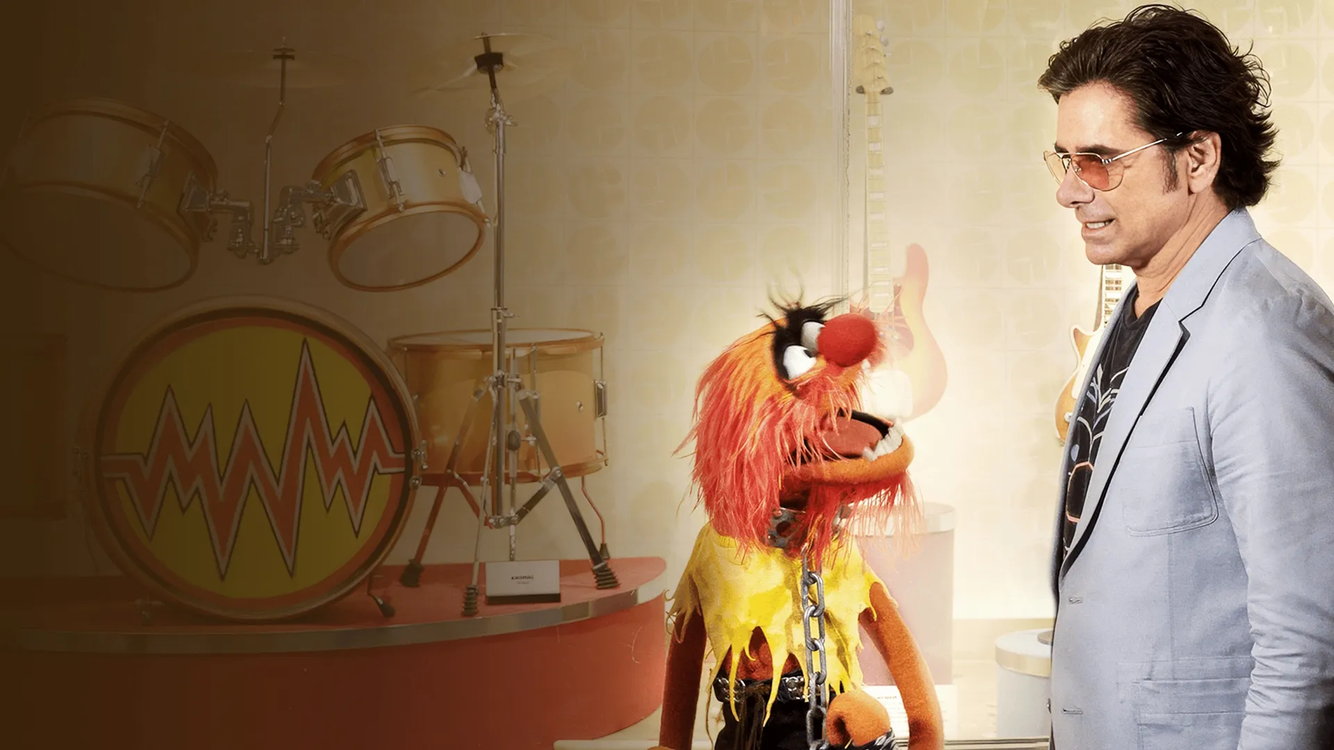 Animal and John Stamos talk in front of a drum set
