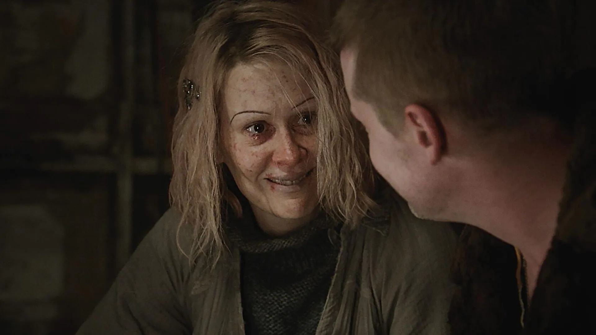 An unkempt woman with very thin eyebrows smiling at a man