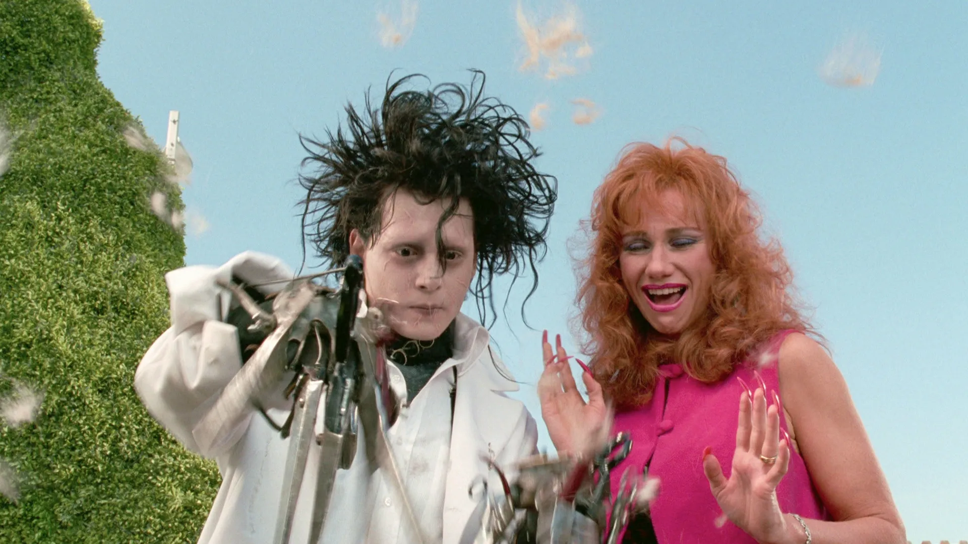 Johnny Depp as Edward Scissorhands using his scissor hands to trim hair alongside Kathy Baker as Joyce in a movie still from Edward Scissorhands.