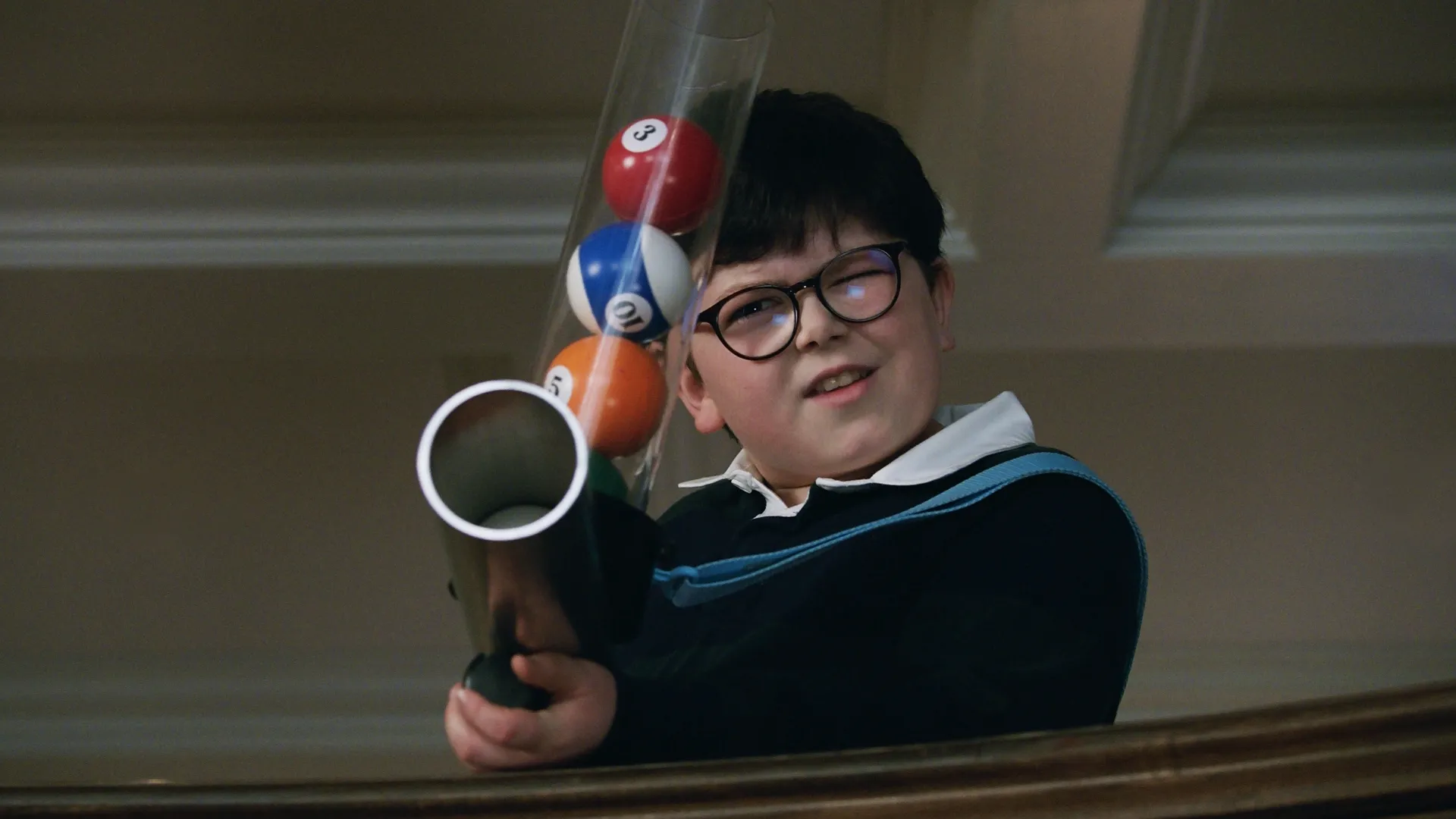 マックス・マーサー（アーチー・イェーツ）が、ビリヤードのボールを装填したお手製銃を構え、画面の外の何かを狙っている