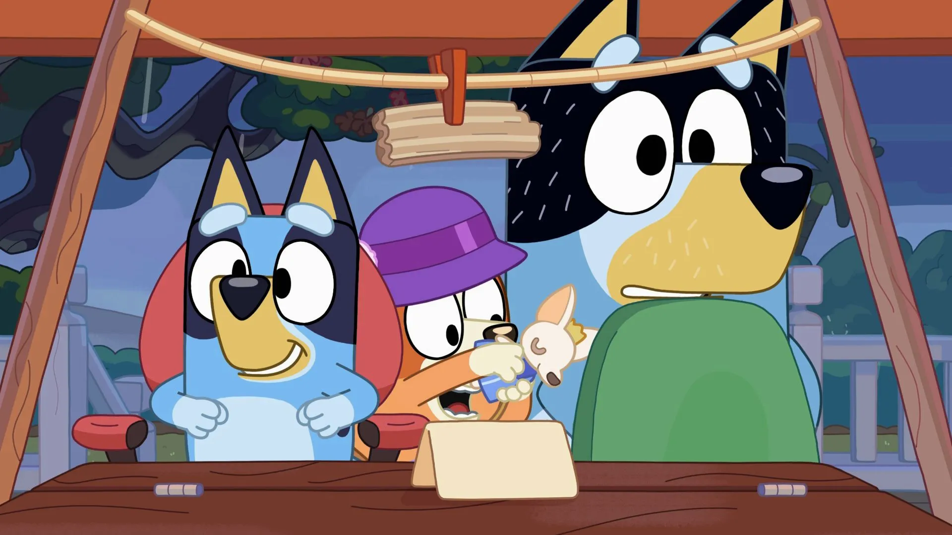 Una escena animada de la serie Bluey que muestra a Bluey sonriendo con entusiasmo junto a Bingo, que usa una gorra morada y sostiene un perrito de juguete, mientras Bandit observa con los ojos muy abiertos bajo una tienda en el patio trasero