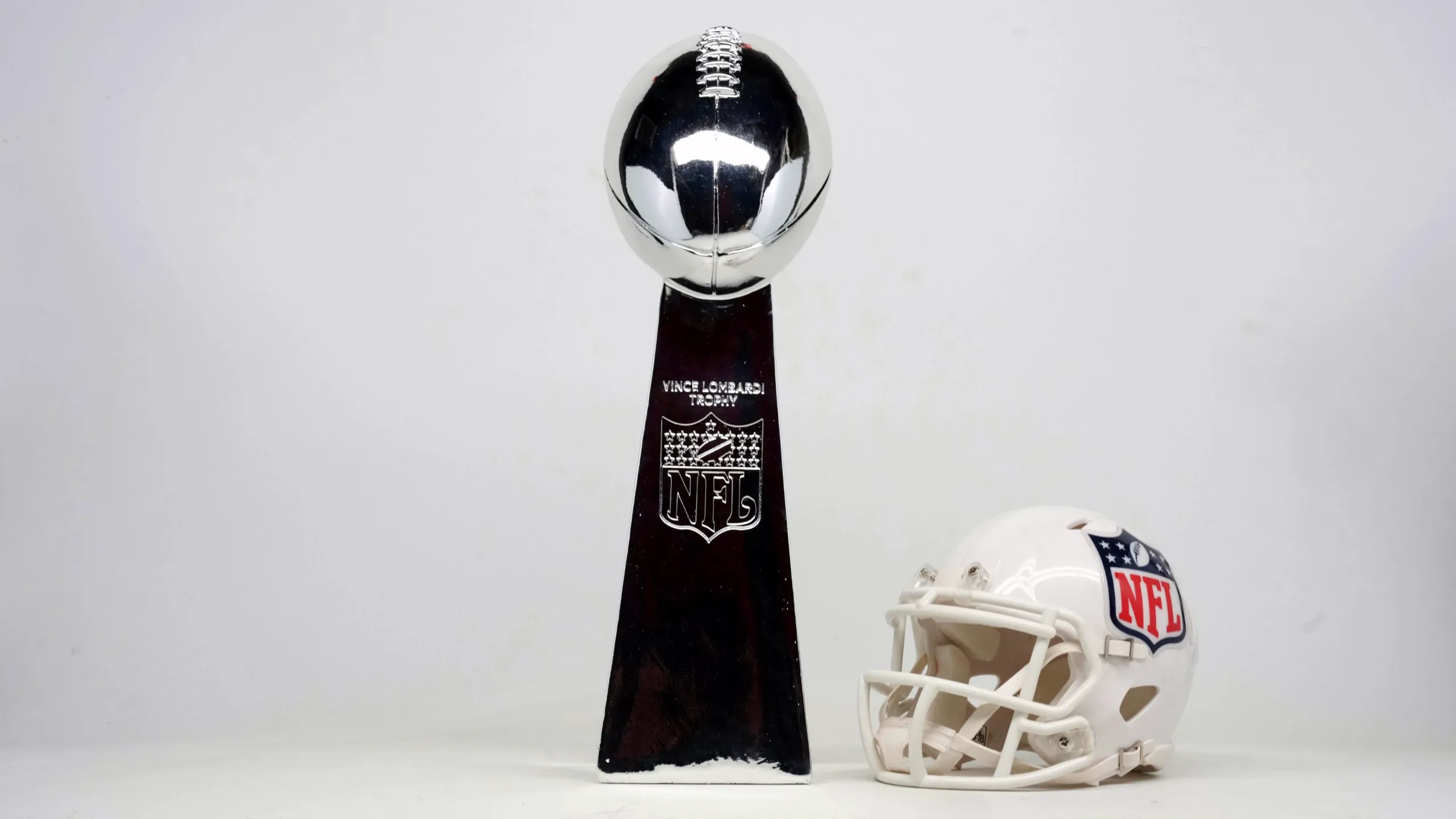 Vince Lombardi Trophy beside a white NFL football helmet.