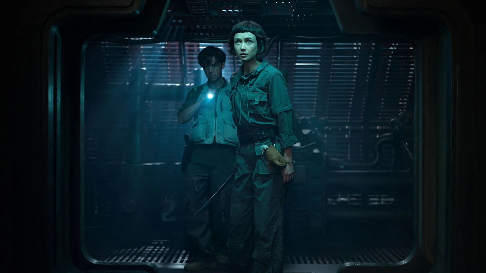 Wendy (right) and Hermit (left) walking down a dark corridor, in Alien: Earth