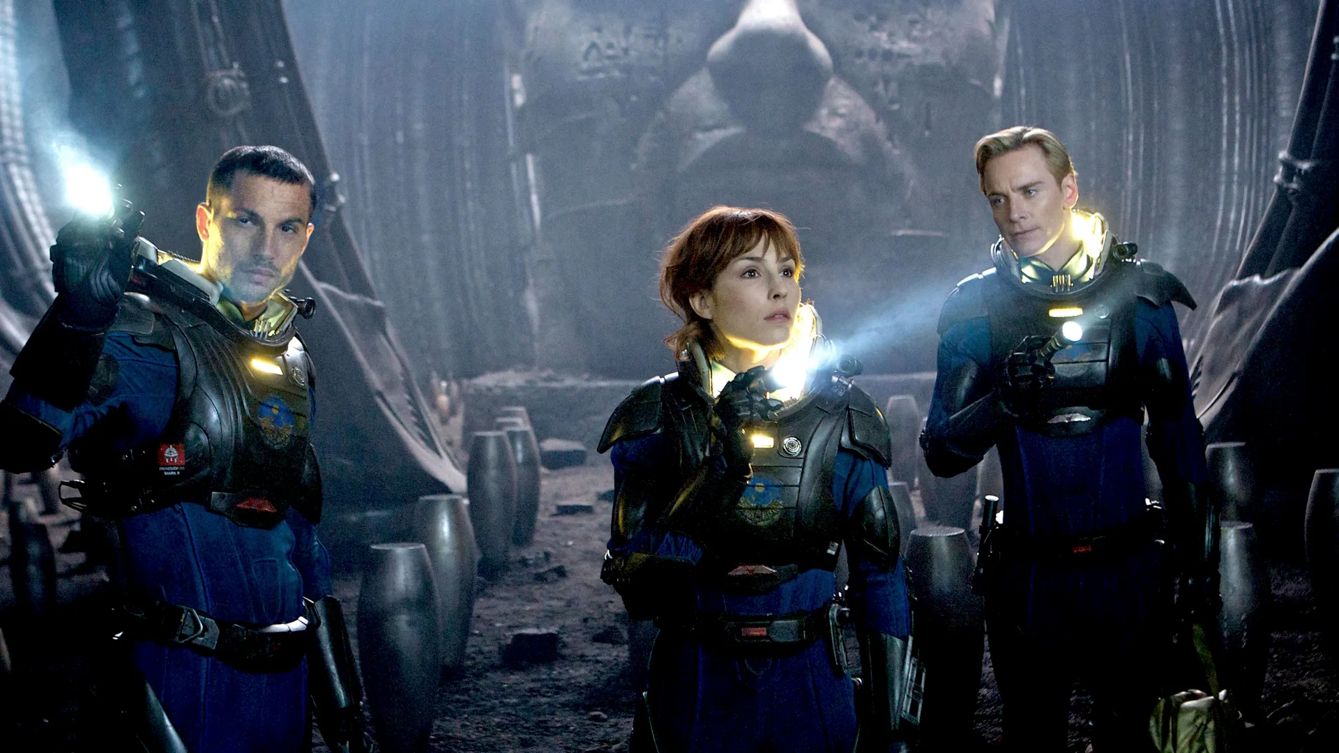 Meredith Vickers, David, and Elizabeth Shaw from Prometheus in front of a patterned blue background.