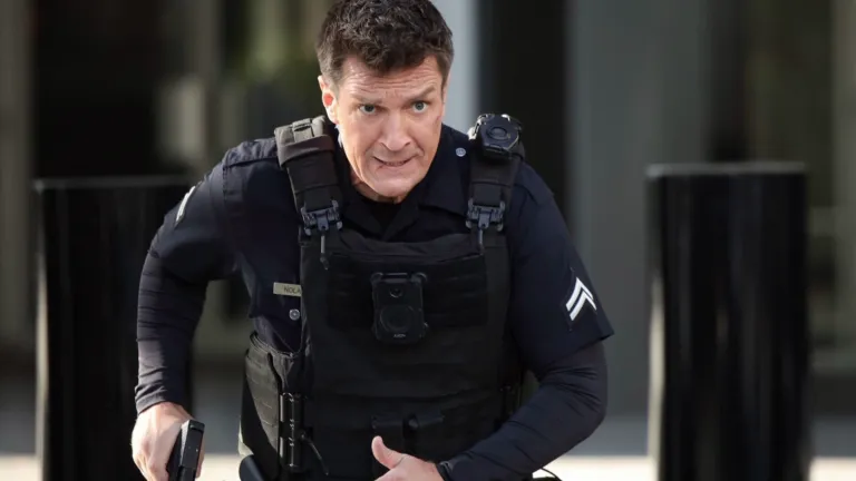 Officer Nolan, played by Nathan Fillion, moves in tactical gear with gun drawn in a tense scene from The Rookie.