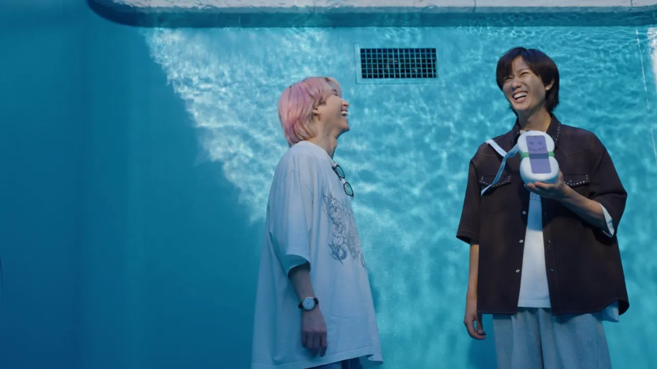 Snow Manのメンバー2人が水族館の大型水槽の前で笑い合いながら会話している様子。