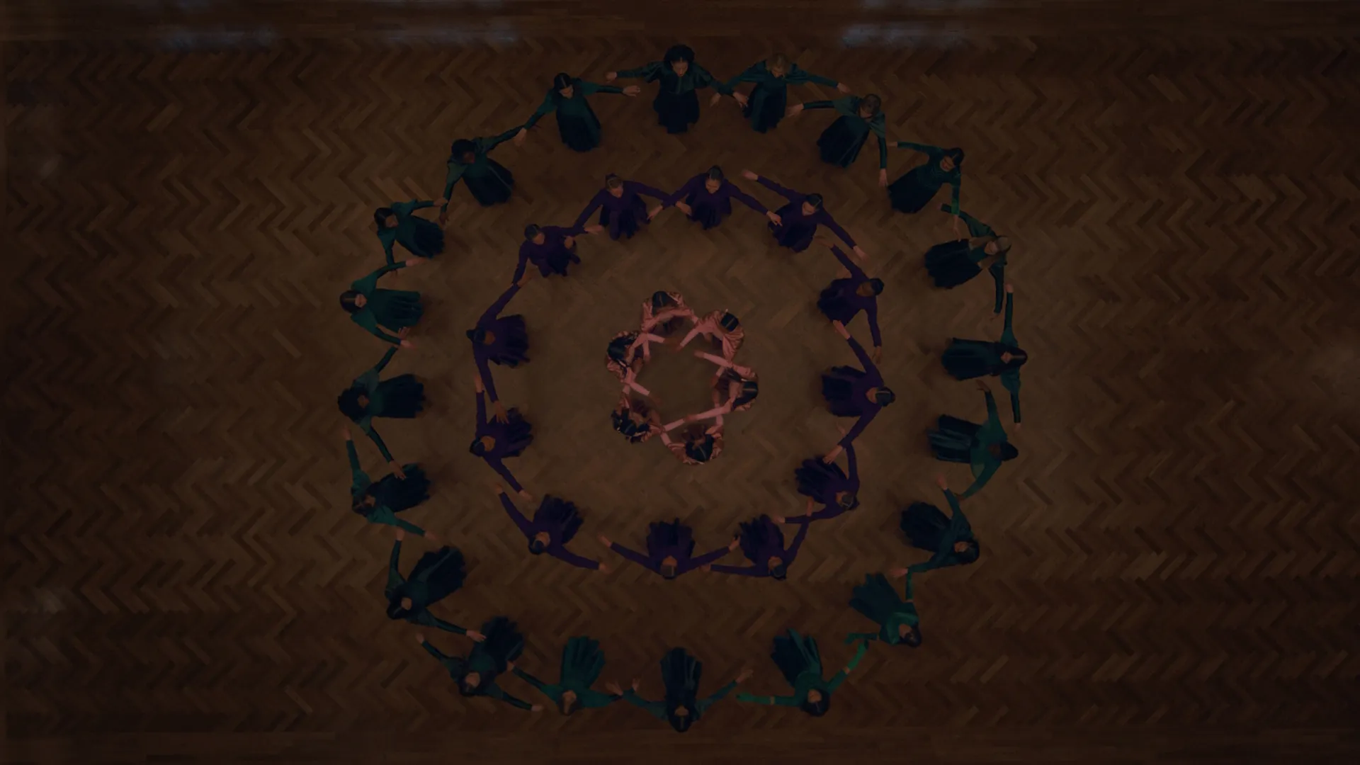 A birds eye view of a large group of people making shapes by holding hands in the circle in The Testaments