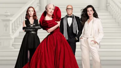 Four actors from the movie The Devil Wears Prada—Emily Blunt, Meryl Streep, Stanley Tucci, and Anne Hathaway—pose together in high-fashion black, red, and white outfits on a grand marble staircase.