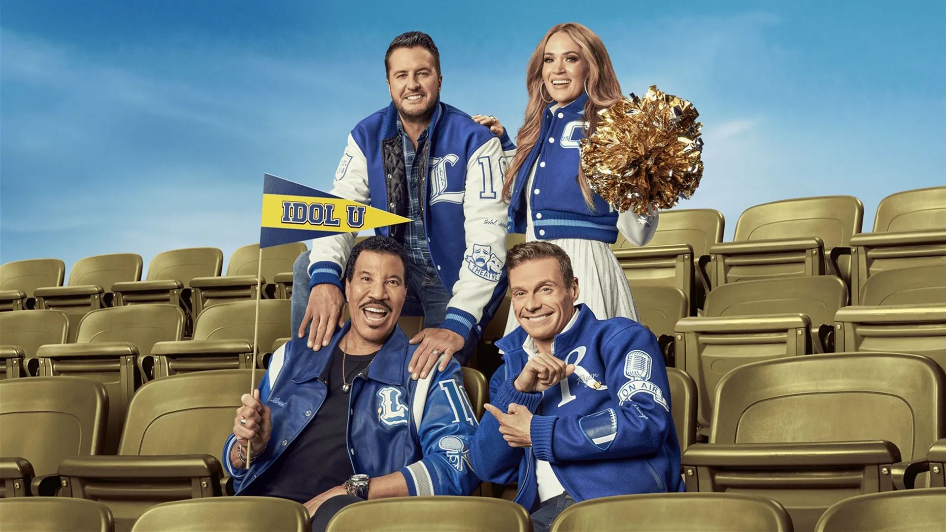 American Idol judges Luke Bryan, Carrie Underwood, Lionel Richie, and presenter Ryan Seacrest sit on bleachers wearing varsity jackets