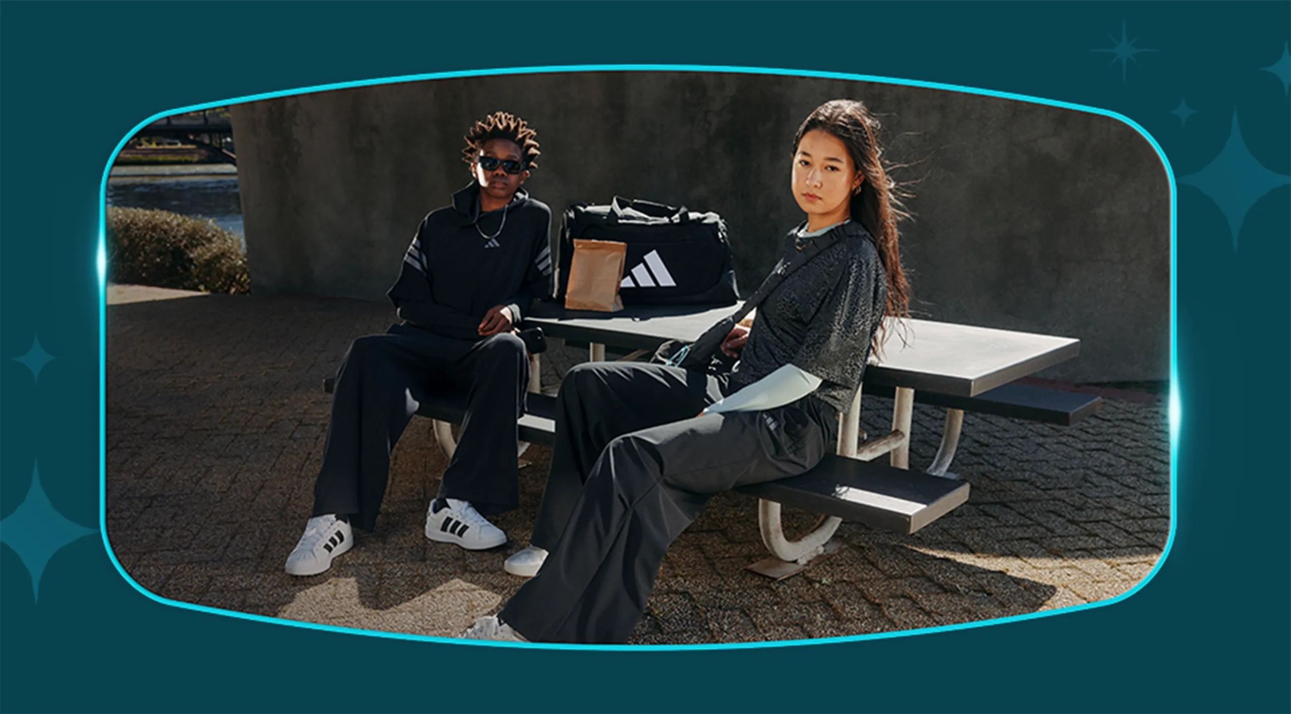 Two adidas models sitting on a bench wearing adidas gear
