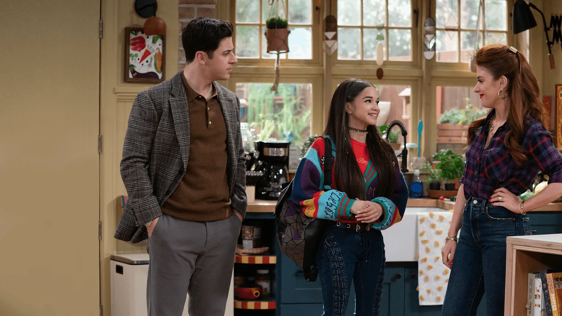 Justin Russo (David Henrie), Billie (Janice LeAnn Brown), and Giada Russo (Mimi Gianopulos) stand in a cozy kitchen, with Justin and Giada sharing a warm glance while Billie looks toward Giada with a bright smile