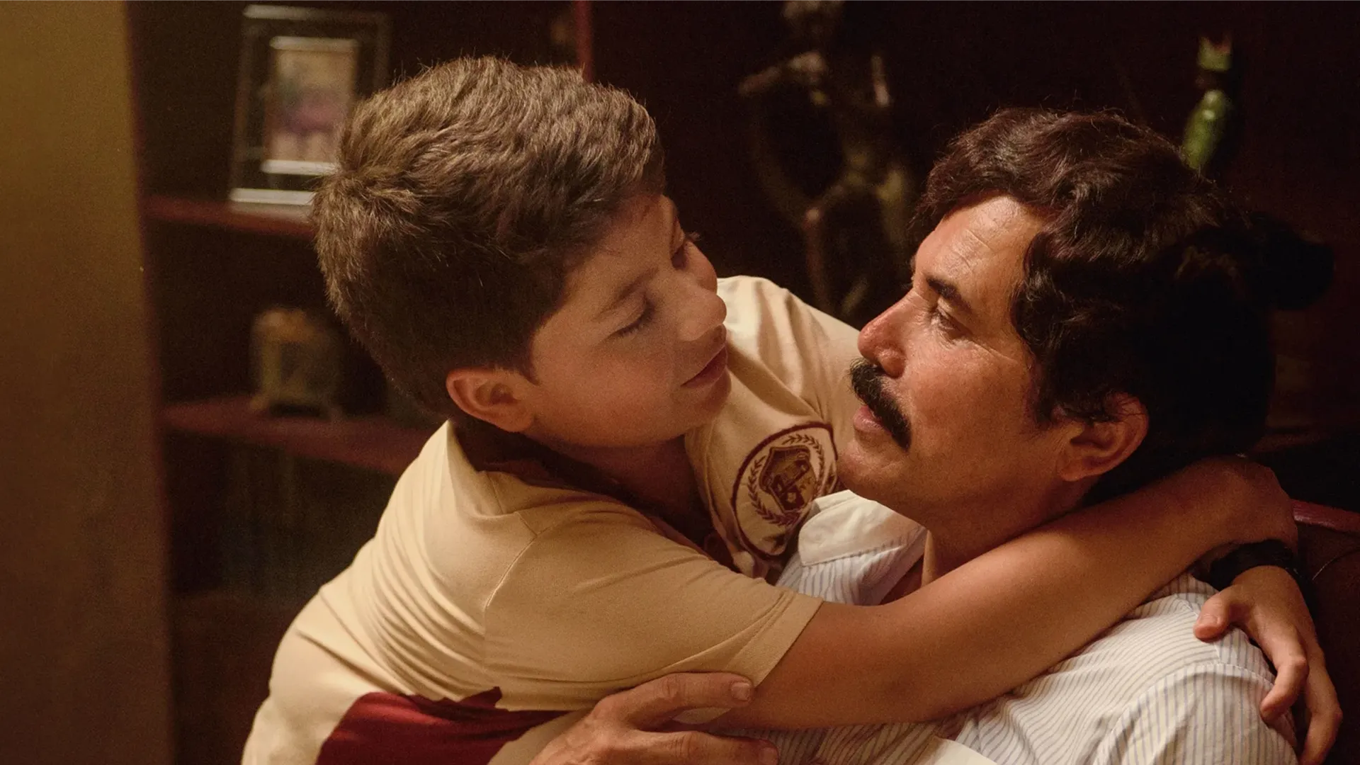 This image is a scene featuring the actor John Leguizamo portraying the Colombian drug lord Pablo Escobar in the television series "Dear Killer Nannies". The series is inspired by the memoirs of Escobar's son, Juan Pablo Escobar, and explores the story from the perspective of a child raised in that environment. 