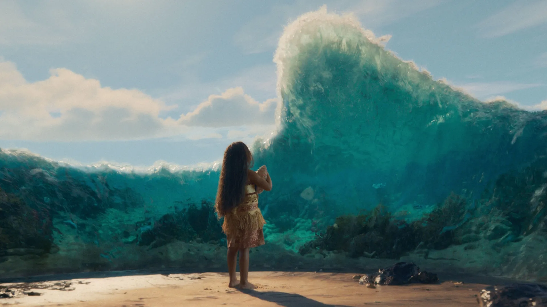 A young Moana stands on a sandy beach from behind, holding a seashell as a massive wall of clear turquoise ocean water parts before her.
