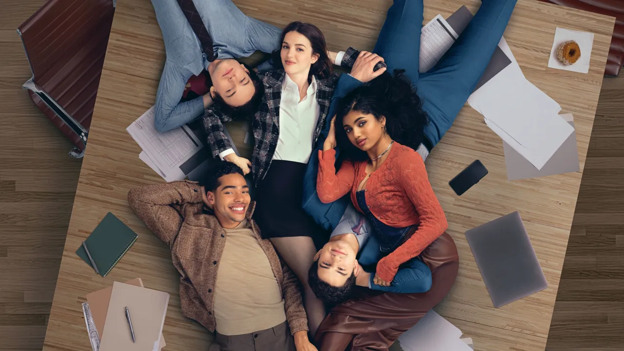 Main cast of Hulu's Not Suitable For Work lying together on a desk in an office.