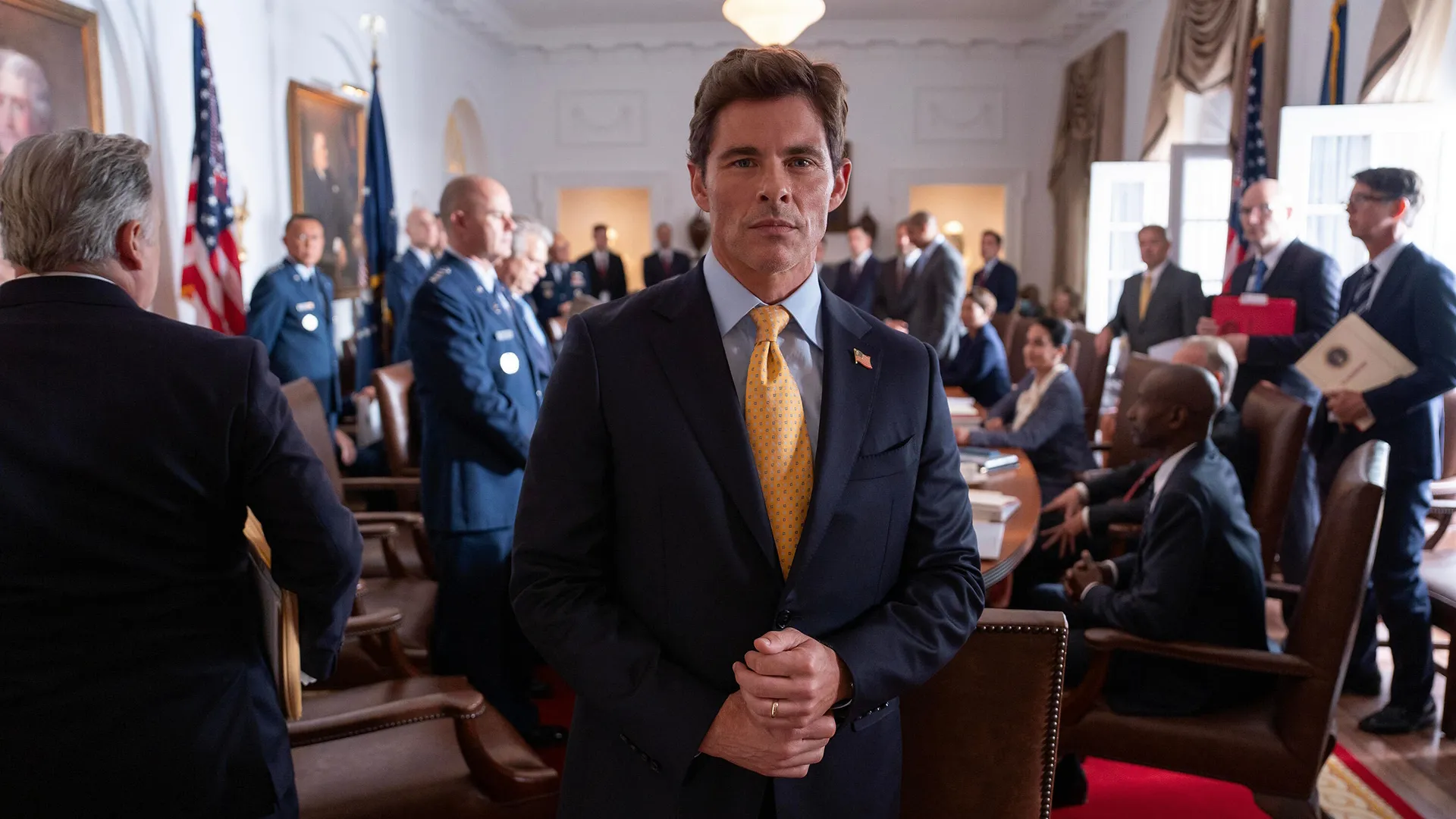 President Cal Bradford (James Marsden) faces the camera in a busy White House room.