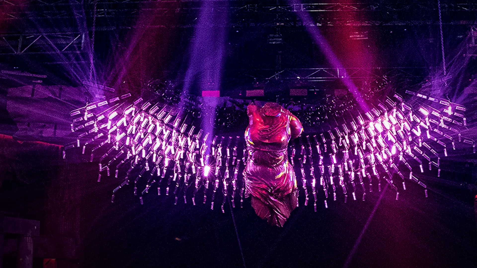 A pink dress in a dark room illuminated by a lot of pink lights.