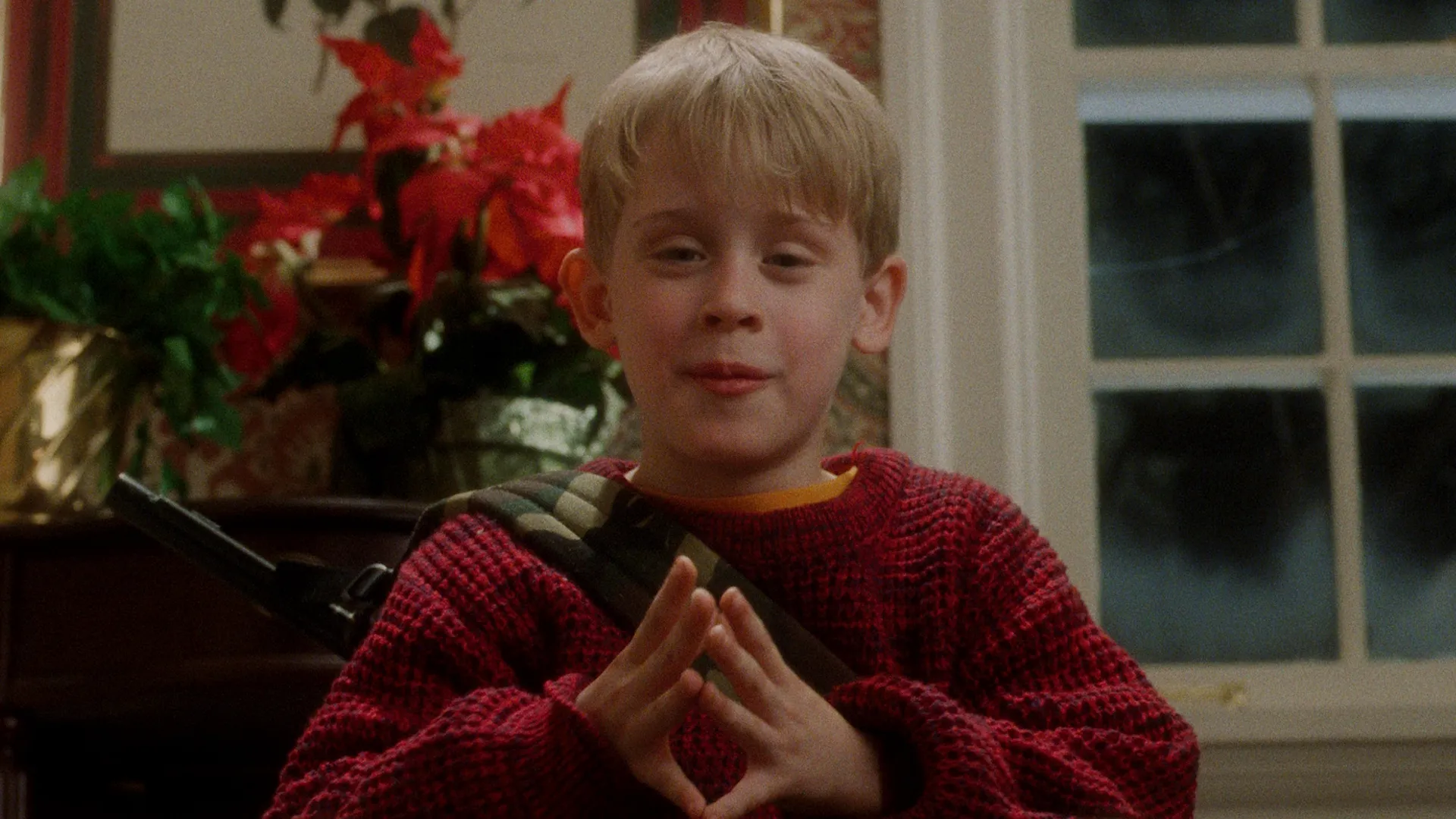 ケビン・マカリスター（マコーレー・カルキン）が窓辺に座り、両手を合わせて何かを企んでいるようなようす