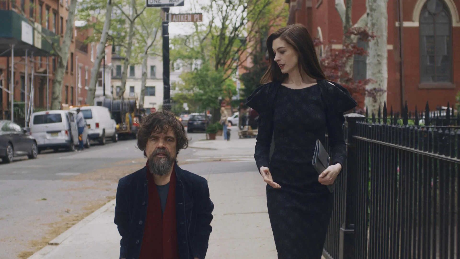 Patricia (Anne Hathaway) walks down a street with her husband (Peter Dinklage) in She Came to Me.