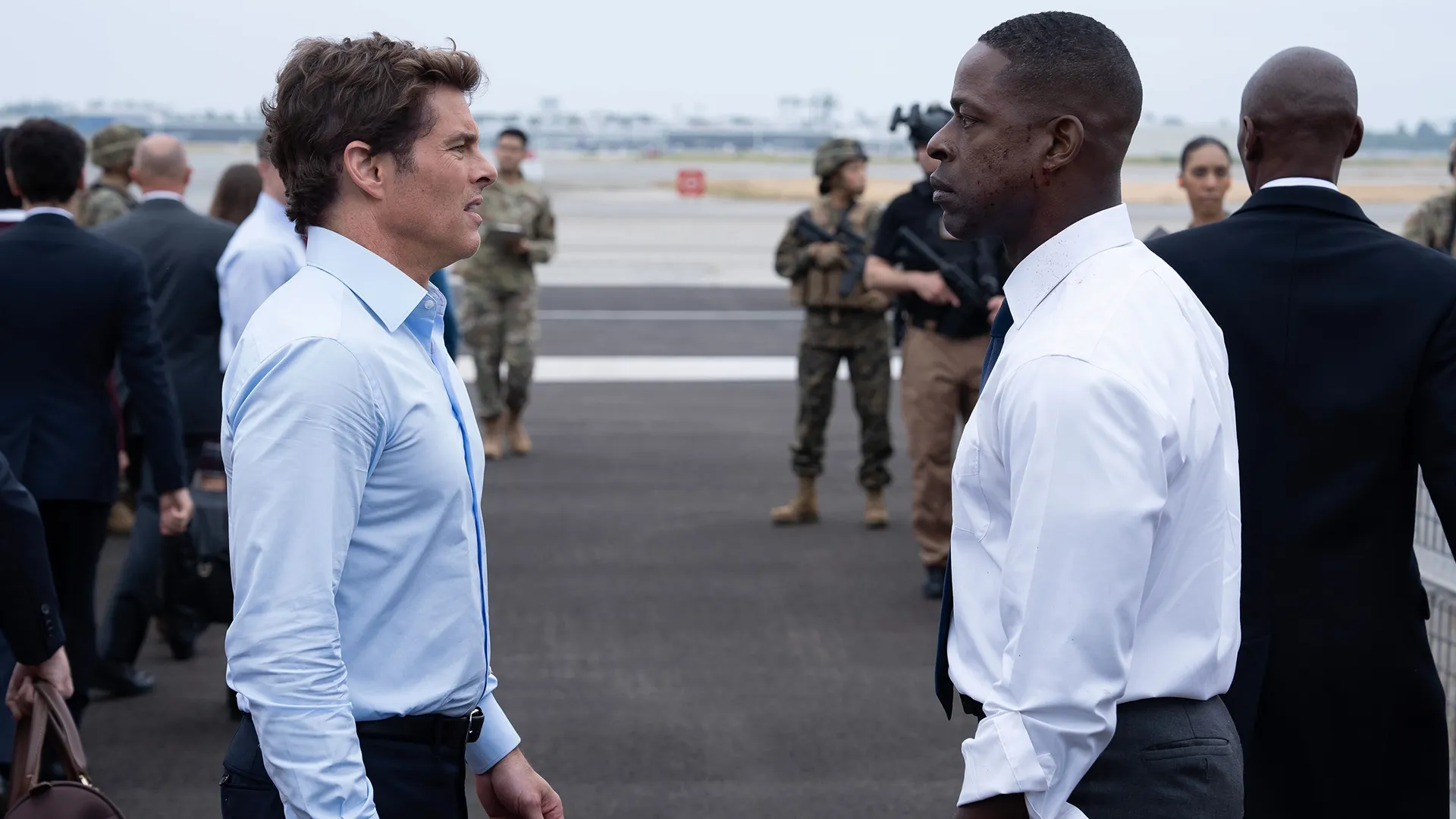 Cal (James Marsden) and Xavier (Sterling K. Brown) face each other on an airport runway, with soldiers and men in suits visible in the background