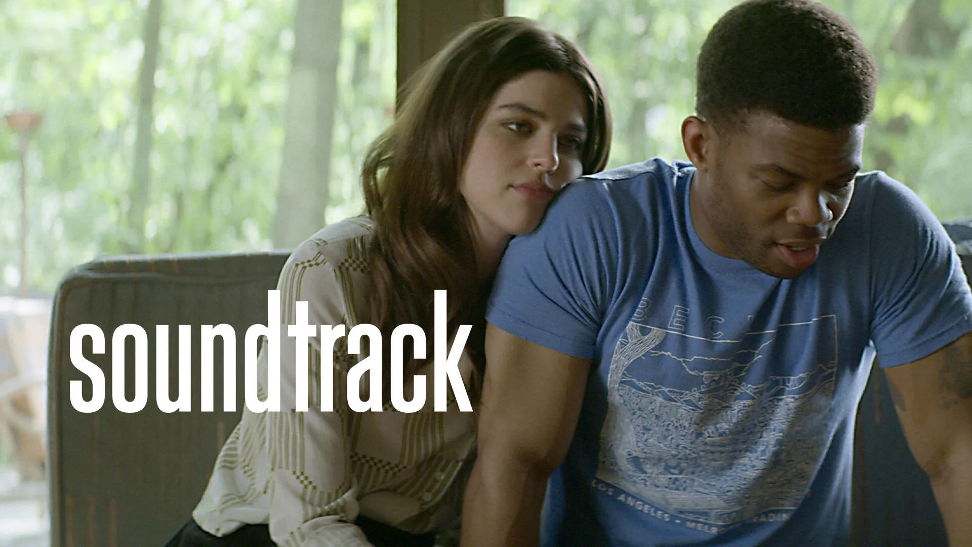 Nellie (Callie Hernandez) rests her head on Samson's (Paul James) shoulder behind the Soundtrack logo