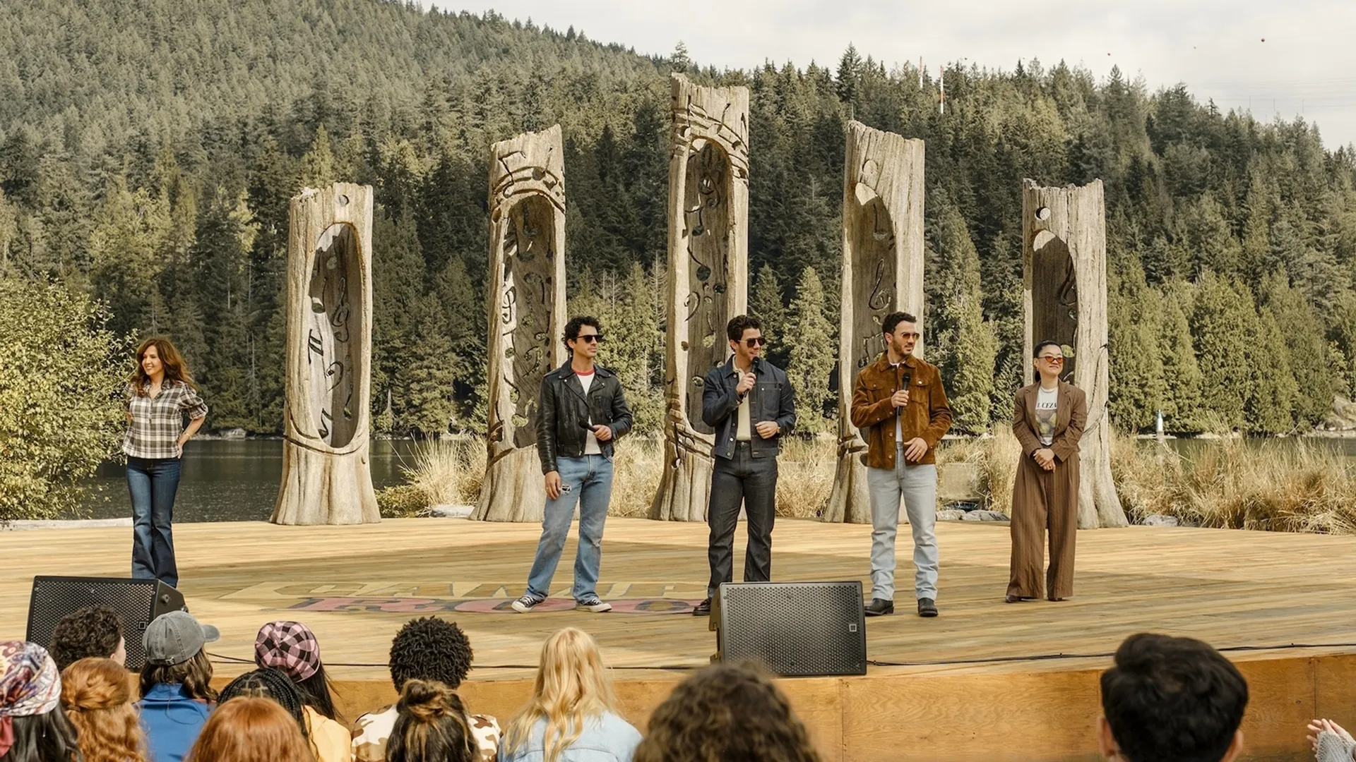The Jonas Brothers filming a scene for Camp Rock 3 on an outdoor lakeside stage