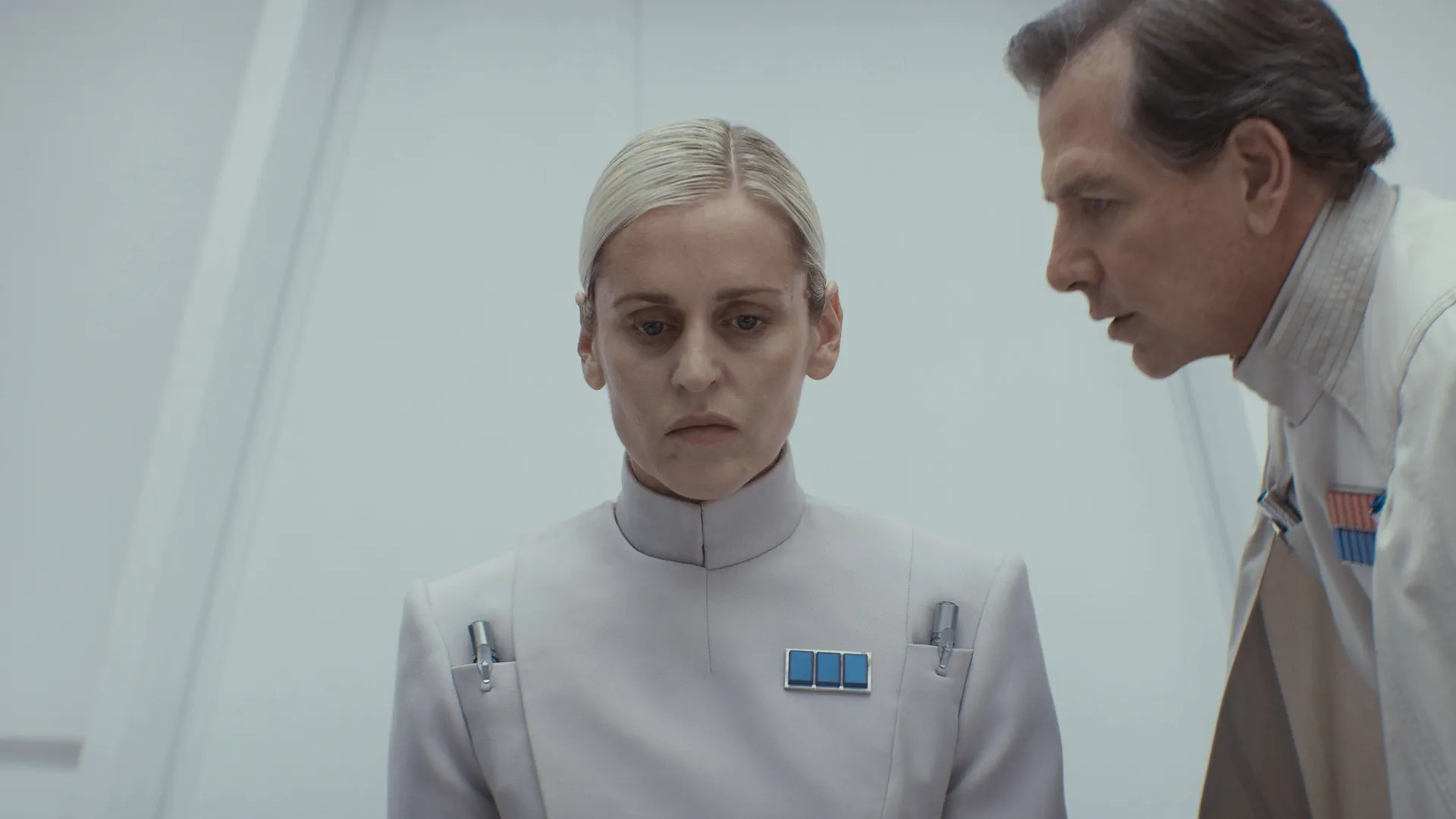 Dedra Meero (Denise Gough) is interrogated by Director Krennic (Ben Mendelsohn) in a white room within an ISB facility.