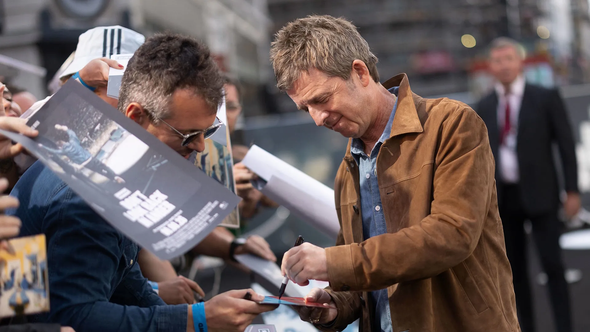 Noel Gallagher signs memorabilia and posters for fans at the London premiere of Oasis: Don’t Look Back in Anger.