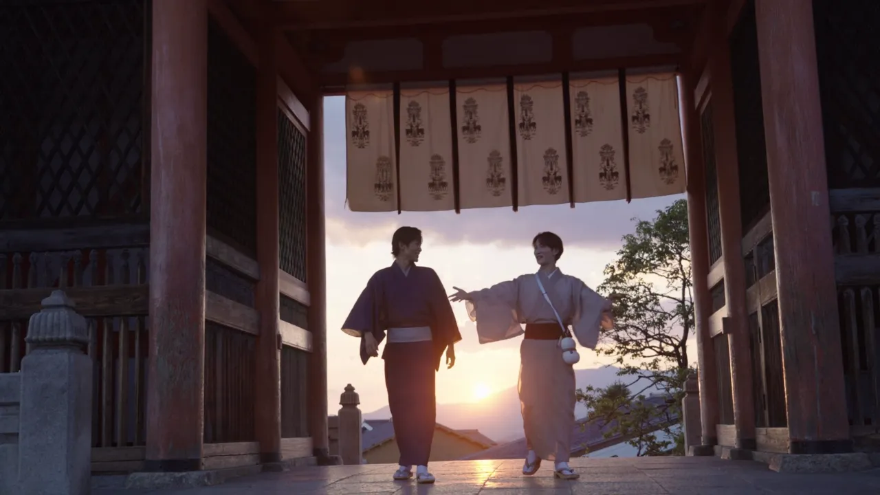 Snow Manのメンバー2人が和服を着て京都の神社の門の前で夕日を背に歩いている様子。