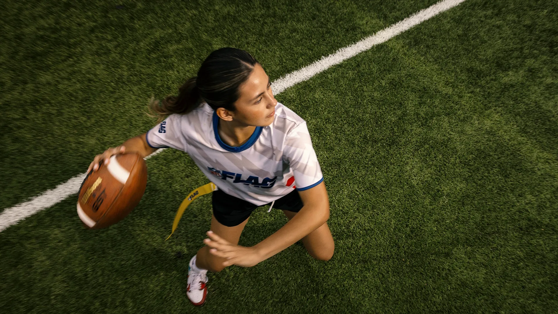 A young woman gets ready to throw the football during a game of flag football.