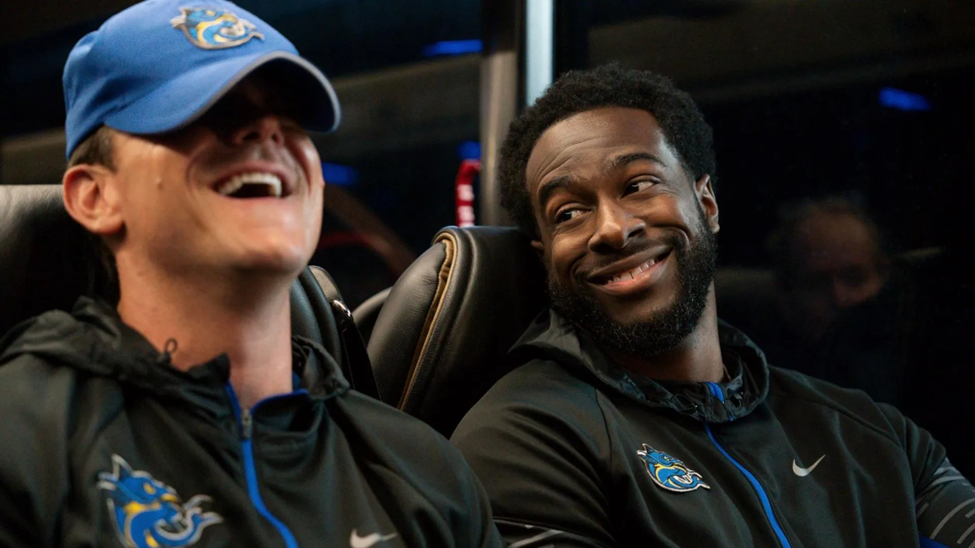 Chad Powers (Glen Powell) sits besides Coach Byrd (Quentin Plair) on the team bus.
