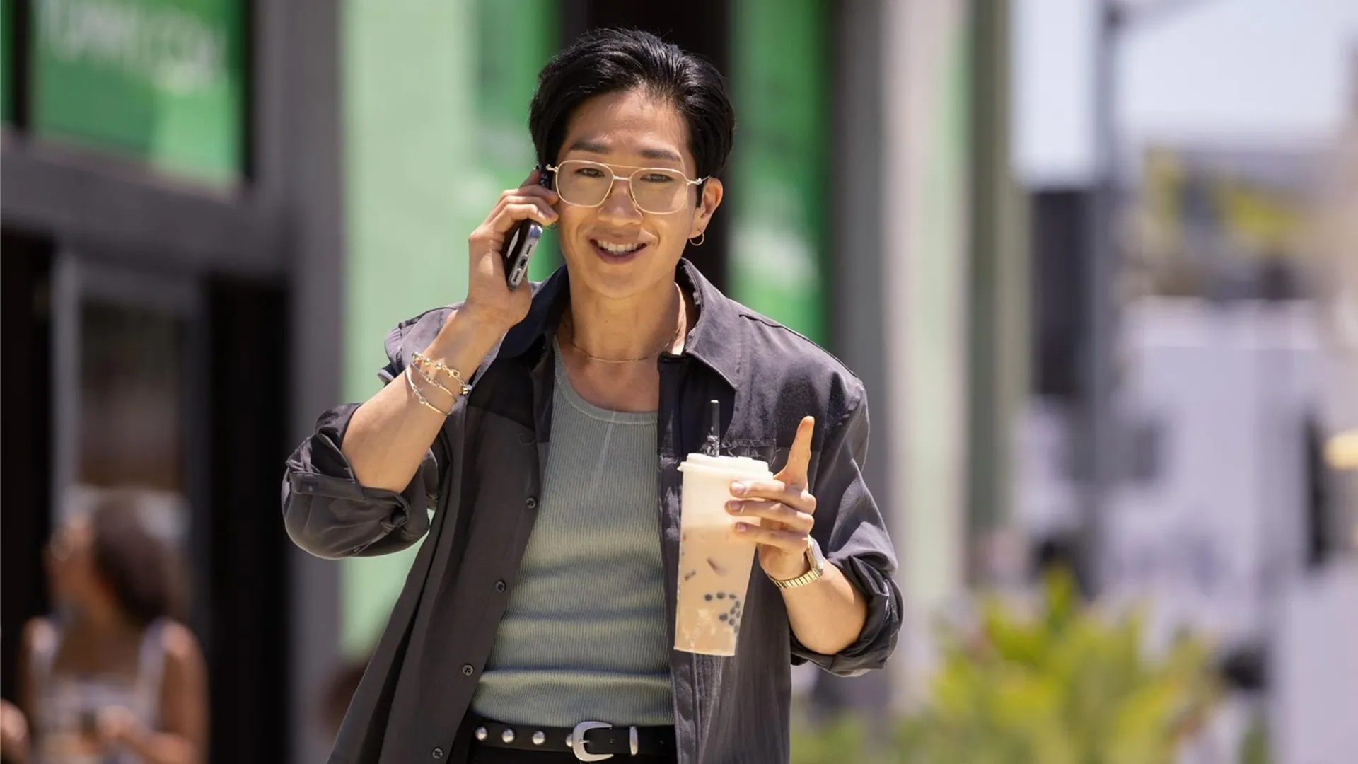 Tim Jo as Daniel Kim, walking down the street talking on the phone and holding a big iced coffee